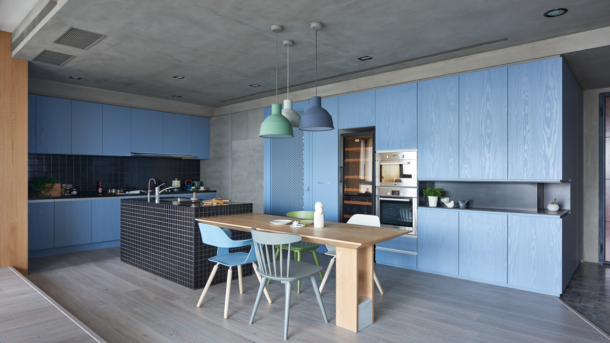Không gian phòng bếp màu xanh được bố trí đảo bếp mặt đá kết hợp bàn ăn gỗ mộc mạc, hài hòa